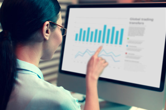 Important detail. The focus being on a pretty dark-haired young woman looking at the computer screen and pointing at a bar chart