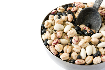 Uncooked assorted legumes with spoon in metal bowl isolated on white background. Copyspace