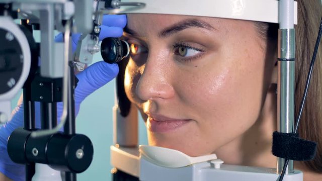 A woman holds eyes open during an optical exam at a ophthalmologist office.
