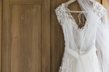 Fototapeta na wymiar Wedding dress hanging against a wooden background
