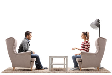 Young couple seated in armchairs having a conversation - Powered by Adobe