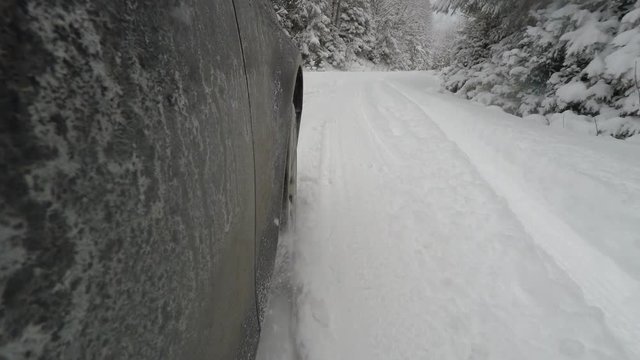 Car skidding in snowy road, side camera view of stucked car