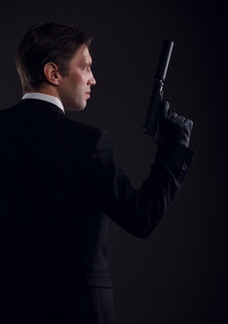Photo from back of gangster man in leather gloves with gun
