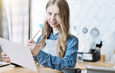 Preparing material. Amazing female person keeping smile on her face and making notes while working in cafe