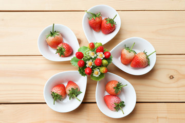 Artificial Strawberry Flowers on centre with freshness fruit on the table wood background