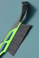 Brush for snow cleaning. Green brush on a metallic green background. Winter. Snow