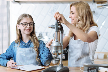 Be attentive. Positive girl keeping smile on her face and holding pen while touching special tool