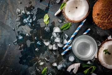 Healthy food concept.  Fresh Organic Coconut Water with coconuts, ice cubes and mint, on rusty dark blue background, copy space