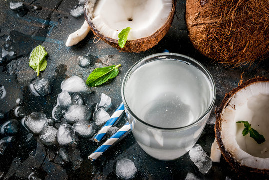 Healthy food concept.  Fresh Organic Coconut Water with coconuts, ice cubes and mint, on rusty dark blue background, copy space