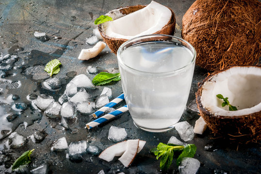 Healthy food concept.  Fresh Organic Coconut Water with coconuts, ice cubes and mint, on rusty dark blue background, copy space