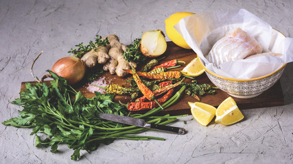 close-up view of healthy raw fish in bowl with vegetables and spices on wooden cutting board