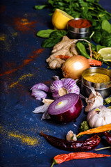 selective focus of parsley, basil, lemon, ginger, peppers, onions and garlic on blue