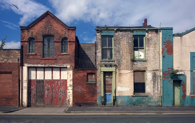 derelict houses and abandoned commercial property on a residential street with boarded up windows...