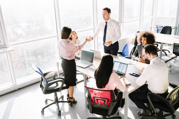 Business consultants working in office. Team lead shaking manager hand for good job.