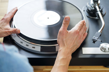 Hands placing record on turntable close-up