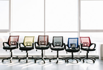 Colorful office chairs standing in a row at big window. Office concept.