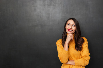 Pensive smiling brunette woman in sweater holding her chin