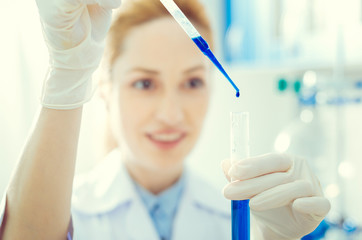 Keeping in a right proportion. Scaled up look on female lab worker holding a test tube and using a...