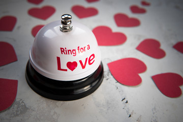 Ring bell for a love and many hearts on a wood background