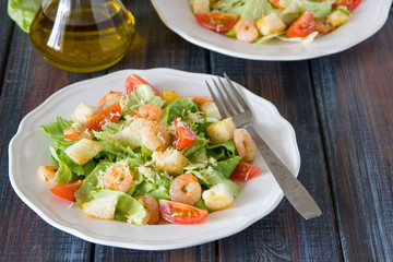 Caesar salad with shrimps on a wooden background