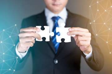Businessman hands connecting puzzle pieces representing the merging of two companies or joint...