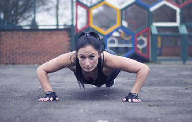 Fitness woman doing push-ups during outdoor cross training workout. Beautiful young and fit fitness sport model training outside