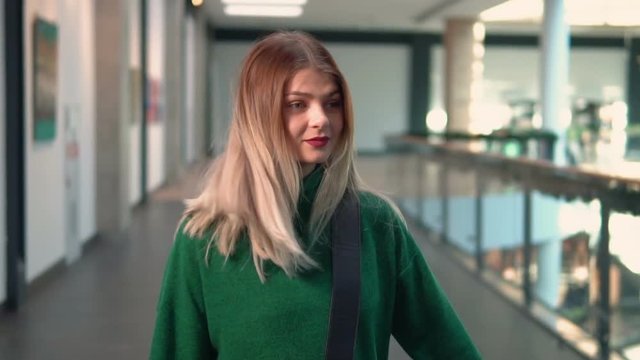 Stylish young woman wears in green walks with fashionable bag, indoor slowmotion