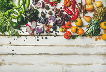 Helathy raw vegan food cooking background. Flat-lay of fresh fruit, vegetables, greens and superfoods over white wooden table, top view, copy space. Clean eating, alkaline diet, vegetarian concept