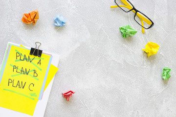 New Idea Creativity Business Concept with a copy space, Plan A, Plan B, PlanC list, glasses and colorful crupmled paper balls on a grey concrete background, flat lay, top view