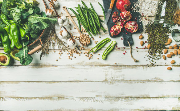 Winter vegetarian, vegan food cooking ingredients. Flat-lay of vegetables, fruit, beans, cereals, kitchen utencil, dried flowers, olive oil over white painted wooden background, top view, copy space