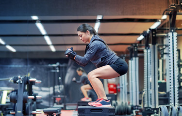 woman doing squats on platform in gym