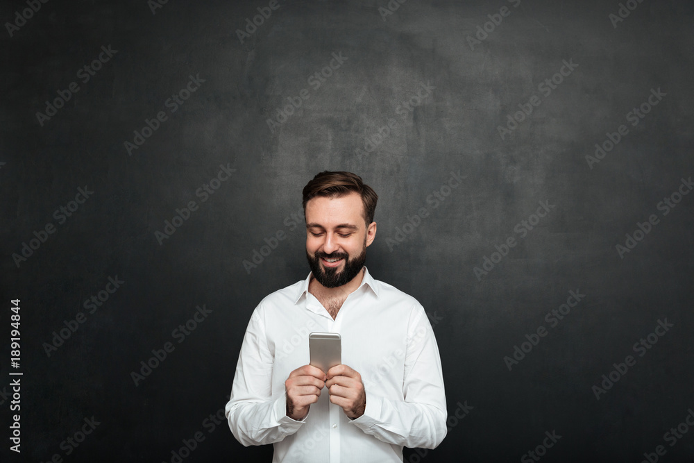 Poster pleased office worker in white shirt typing text message or scrolling feed in social network using c