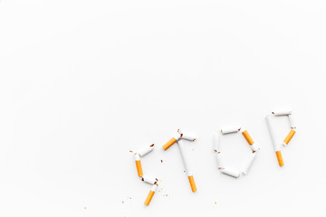 Stop smoking. Word stop lined cigarettes on white background top view copy space