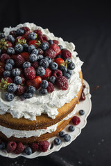 Beautiful, fruit naked cake on a dark tablecloth 