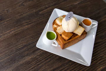 Honey toast with ice cream in dish on wooden table