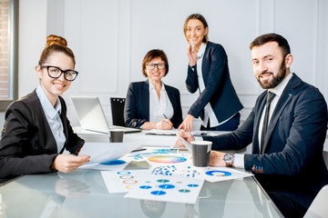 Portrait of a business people working with charts and documents sitting at the table during the conference in the office