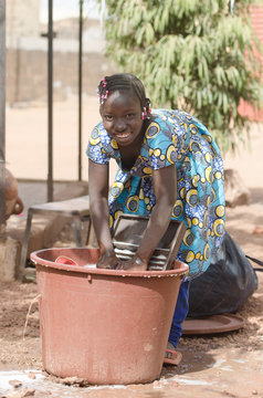 Little African Girl Working at Home Washing Clothes Outdoors