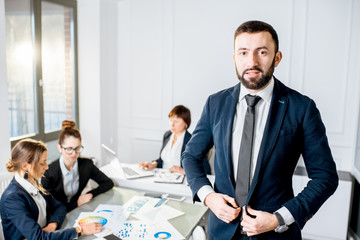Portrait of a handsome businessman standing during the conference with colleagues in the office
