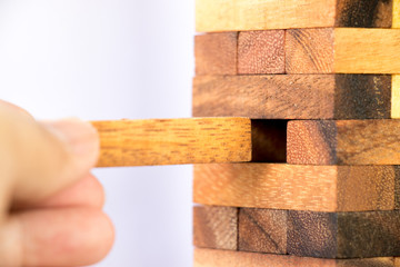 Hand hold wood block out of the stack up as tower on white background