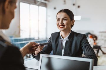 attractive young businesswoman giving passport and ticket to staff at airport check in counter