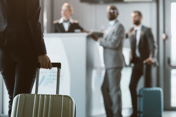 cropped shot of businesswoman with luggage walking to airport reception