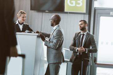 queue of businessmen at airport reception to buy tickets