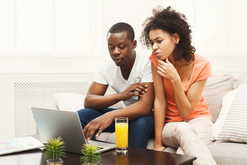 Young african-american couple working on laptop, copy space