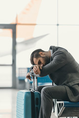 exhausted businessman sleeping at airport lobby while waiting for flight