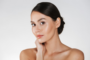 Fototapeta premium Beauty portrait of charming caucasian woman with brown hair in bun posing at camera with beautiful look, isolated over white background