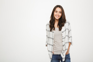 Smiling brunette woman in shirt posing with arms in pockets