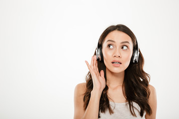 Fototapeta premium Mystery brunette woman in headphones listening music and looking away