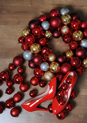 Christmas composition. Red lacquered shoes with heels and a wreath of Christmas balls, top view