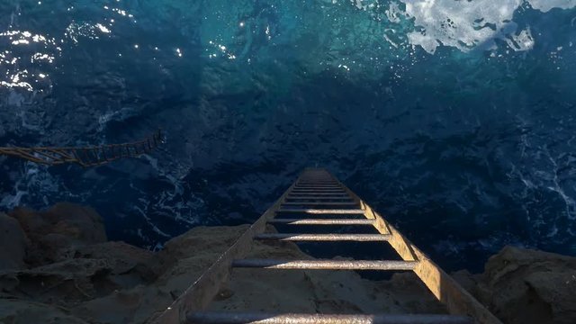 A swaying steel ladder going down into the sea