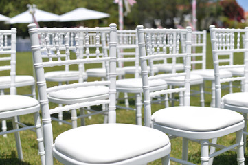 Beautiful arrangement for wedding ceremony event on the natural outdoors lawn park background. Flowers, tables, chairs, elegant romantic decoration details and luxury gathering lifestyle